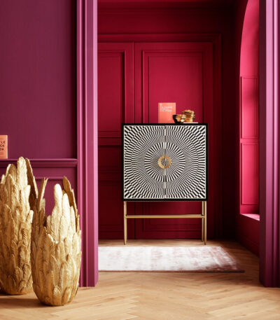 Black and white sunburst-pattern floor cabinet with brass handle and metal legs