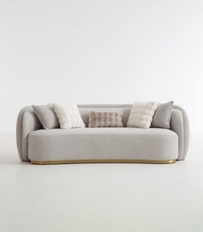 Curved 3 seater warm grey fabric sofa with gold-toned base and scatter cushions