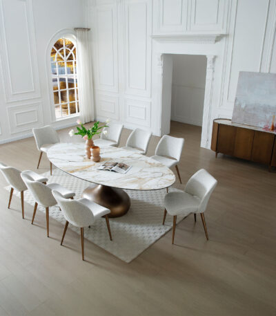 Oval gold-veined ceramic dining table with bronze pedestal base and light grey fabric chairs