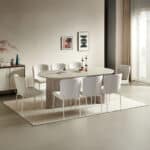 Oval stone-look dining table with fluted pedestal base and eight beige fabric chairs