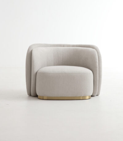 Warm grey curved fabric sofa chair with brass-toned base and deep seat cushion