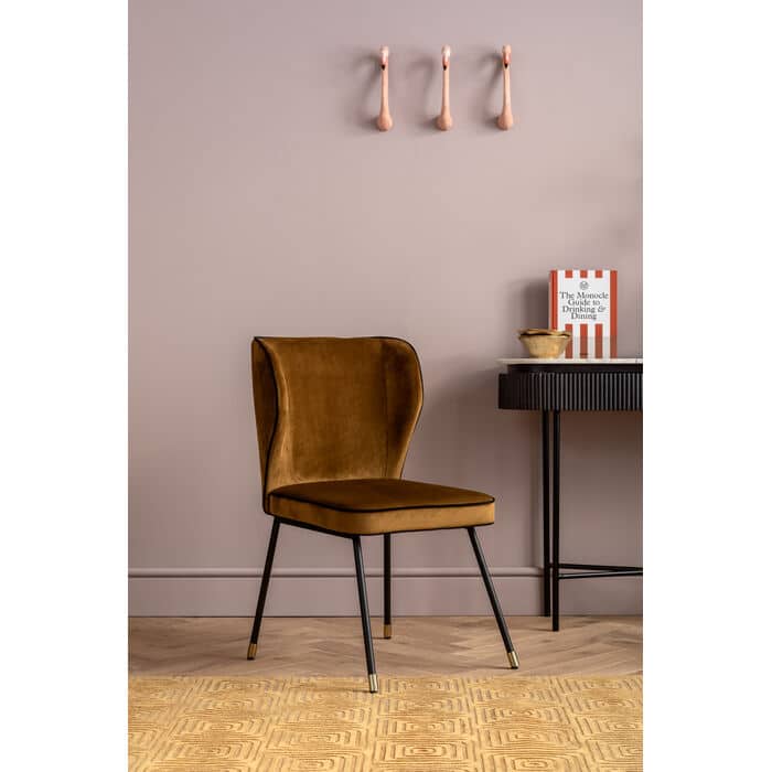 Mustard yellow velvet dining chair with wingback design and black steel legs
