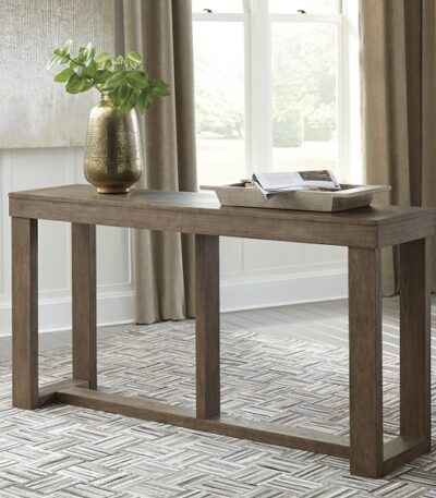 Weathered oak brown solid wood sofa table with open trestle base behind a sofa