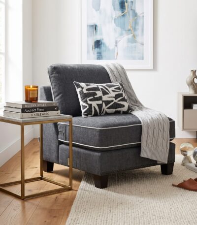 Charcoal grey fabric armless chair with white piping and graphic scatter cushion